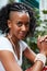 Young black woman sits outdoors looking to camera, vertical