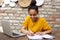 Young black woman sitting at cafe with laptop and notebook