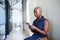 A young Black woman texts while sitting and waiting in office corridor