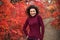 Young blackhaired woman in red sweather posing on camera in red autumnn bushes