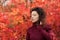 Young blackhaired woman in red sweather posing on camera in red autumnn bushes