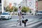 Young blind man with white cane and guide dog walking across street in city.