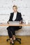 Young blond beauty businesswoman sitting at a office table with laptop, notebook and glasses in suit. Business concept.