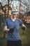 Young blond boy with a hat is chopping branches for later burning. Processing cut branches from fruit trees in orchards. Cutting