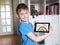 Young blond boy showing painted rainbow on tablet computer in his room. Educating and playing