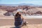 Young blond caucasian girl sitting and admiring outstanding landscape of untouched nature in Atacama desert, Chile