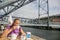 Young blond Caucasian woman drinking coffee, bridge view of city of Porto