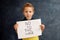 Young blond child, holding sign in support to peace, no war wanted, kid wishing peaceful life