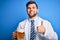 Young blond doctor man with beard and blue eyes wearing coat drinking jar of beer happy with big smile doing ok sign, thumb up