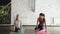 Young blond girl is enjoying individual yoga practice with friendly female instructor in light studio. Women are doing