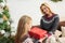 Young blond haired woman giving Christmas gift to her teenage daughter