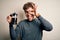 Young blond man with curly hair making coffee using coffemaker over white background with happy face smiling doing ok sign with