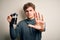 Young blond man with curly hair making coffee using coffemaker over white background with open hand doing stop sign with serious