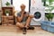 Young blond man doing laundry using smartphone asking to be quiet with finger on lips