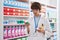 Young blond man pharmacist holding toothpaste bottle at pharmacy