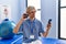Young blond man pysiotherapist using smartphone press hand at rehab clinic