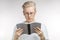 Young blond man reading book over white background with copy space