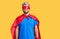 Young blond man wearing super hero custome puffing cheeks with funny face