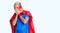 Young blond man wearing super hero custome with sad expression covering face with hands while crying