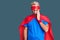 Young blond man wearing super hero custome touching mouth with hand with painful expression because of toothache or dental illness