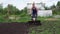 Young blond muscular farmer cultivates ground soil with rotary mini tiller.