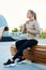 Young blond restful sportswoman in activewear sitting on wooden bench