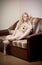 Young blond sensual woman sitting on sofa relaxing with a huge teddy bear