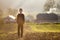 Young blond serious tired child boy standing alone on field after harvest on late summer or autumn sunny day on distant foggy