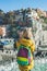 Young blond tourist woman looking at Riomaggiore, Cinque Terre, Italy