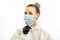 Young blond woman adjusts surgical mask on her face