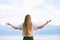 Young blond woman with arms wide open enjoy landscape of cloudy mountains