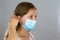 Young blond woman attaching surgical mask to her face