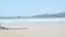 Young blond woman with blue bikini and straw hat sits on the beach and looks at the sea