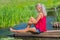 Young blond woman daydreaming at water in nature