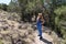 Young blond woman hiker wearing goofy American patriotic clothing and sunglasses on a dirt trail at the ghost town of Old