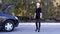 Young Blond Woman Hitchhiking on Road near Car