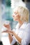 Young blond woman holding cup and tasting coffee