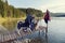 Young blond woman on a motorcycle on a pier on a lake in the mountain with two dogs