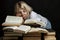 Young blond woman with a pile of books. Black background. Knowledge and education