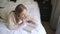 Young blond woman reads book lying on large bed