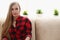 Young blond woman sit on sofa in room