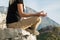 Young blond woman sitting on the edge of the mountain in yoga meditation position cliff against beautiful mountains peak