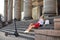 Young blond woman, sitting on staircase of old historical building with pillars in city center. Female portrait with electric