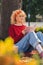 Young blond woman sitting under the tree and reading in park full shot copy pace