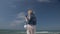 Young blond woman with a smartphone in hand against the background of the sea and blue sky Slow motion