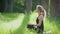 Young blond woman in a sporty suit meditating in nature, woman sitting in lotus position, hands on knees on green grass