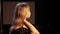 Young blond woman is standing in dark room and talking with somebody gesturing hands in slow motion