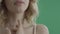 Young blond woman strokes her lips, neck and shoulder against green screen