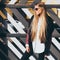 Young blond woman in sunglasses and a fashionable outfit posing on the street warm spring evening. Fashion blogger.