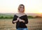 Young blond woman, wearing black jacket and jeans shorts, posing on wheat field on summer evening. Creative stylish three-quarter